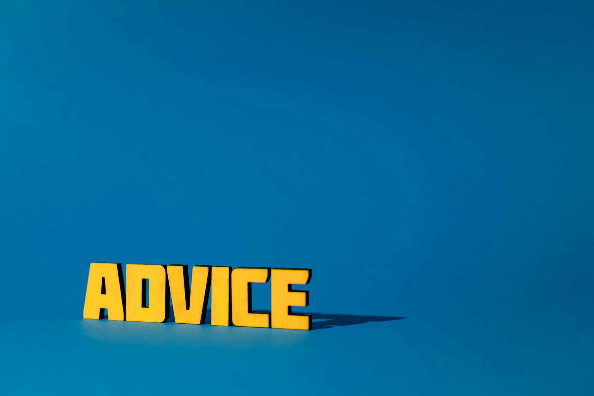 Yellow letters spelling 'Advice' on a vibrant blue background with ample copy space.